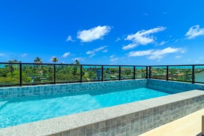 Ein Rooftop-Infinity-Pool mit freiem Blick auf die Skyline und Palmen.