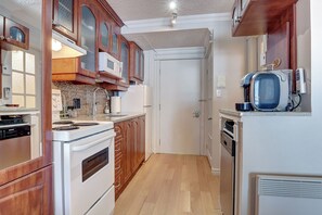 A kitchen with wooden cabinets, a white stove, and a coffee maker. - Au p'tit cocon sur le lac (Magog)
