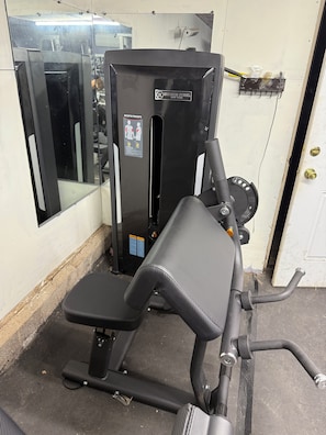 A gym with a weight machine, a mirror, and a door.