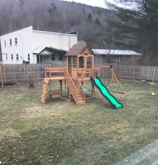 Una estructura de juego de madera con un tobogán en un patio trasero.