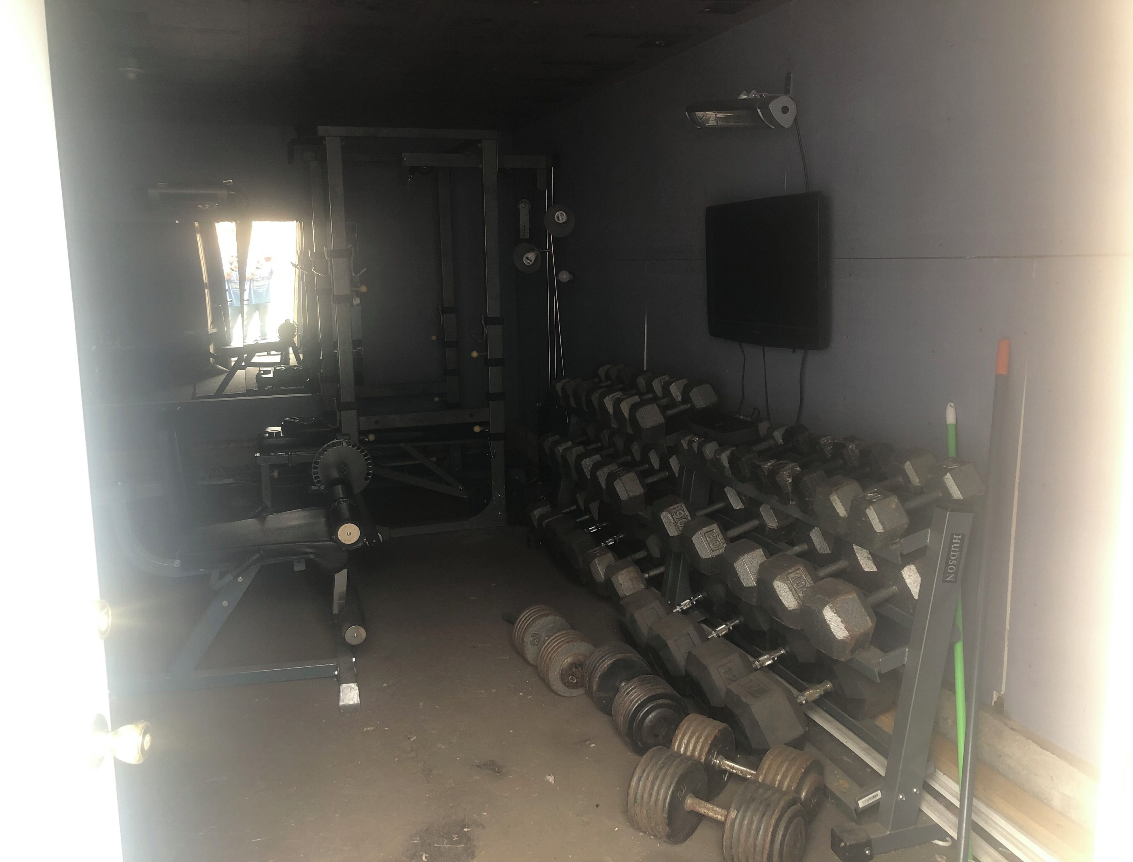 Une salle de sport équipée de matériel de musculation, notamment des haltères et des barres.