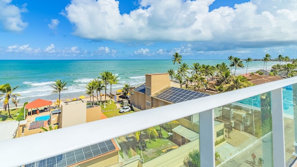 Um imóvel à beira-mar com piscina, painéis solares e vista para o oceano.