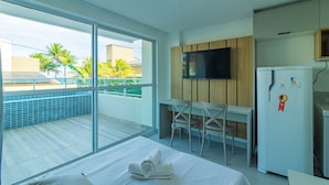Quarto de hotel com cama, escrivaninha, televisão e frigorífico.