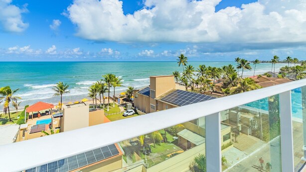 Una propiedad frente al mar con piscina, paneles solares y vistas al océano.
