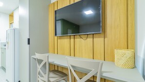 Una cocina moderna con televisor integrado, sillas blancas y un panel de pared de madera.