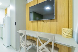 A modern kitchen with a built-in TV, white chairs, and a wooden panel wall. - Ocean Blue #05 - Studio With Pool by Carpediem (Ipojuca)
