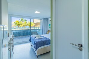A hotel room with a bed, a dining area, and a view of a pool and palm trees. - Ocean Blue #05 - Studio With Pool by Carpediem (Ipojuca)