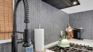 Une cuisine moderne dotée d’un évier en acier inoxydable, d’une cuisinière à gaz et d’un dosseret décoré d’un motif en chevrons.