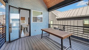 Une terrasse en bois avec une table et des chaises, un mur décoré de motifs et une vue sur un immeuble.