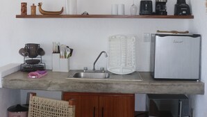 Uma cozinha compacta com pia, micro-ondas, geladeira e uma mesa de jantar de madeira.