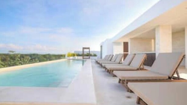 Um hotel moderno com piscina, espreguiçadeiras e vista para a paisagem.