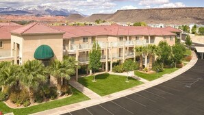A multi-story hotel with a red-tiled roof, a green awning, and a parking lot. - WorldMark St. George - 3 Bedroom (St. George)