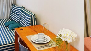 Una habitación acogedora con un sofá a rayas, una mesa de madera con una taza y platillo, y detalles decorativos en la pared.