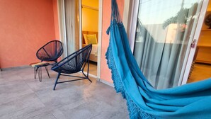 Una habitación con una cama, una hamaca y dos sillas.