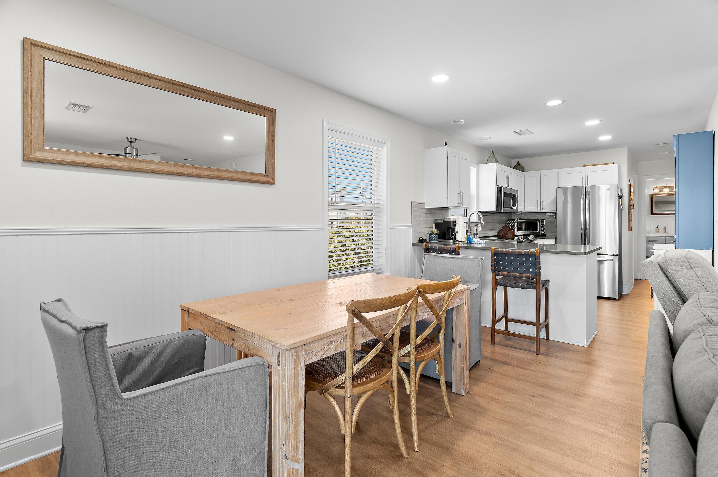 Una cocina moderna con armarios blancos, un refrigerador de acero inoxidable y una mesa de comedor de madera con sillas.