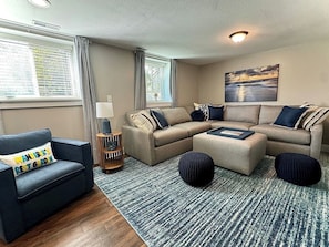 A living room with a sofa set, ottomans, a lamp, and a painting on the wall. - 2BR Winona Lake Garden Suite | Walk to Village |   Dog Friendly | Near Grace (Winona Lake)
