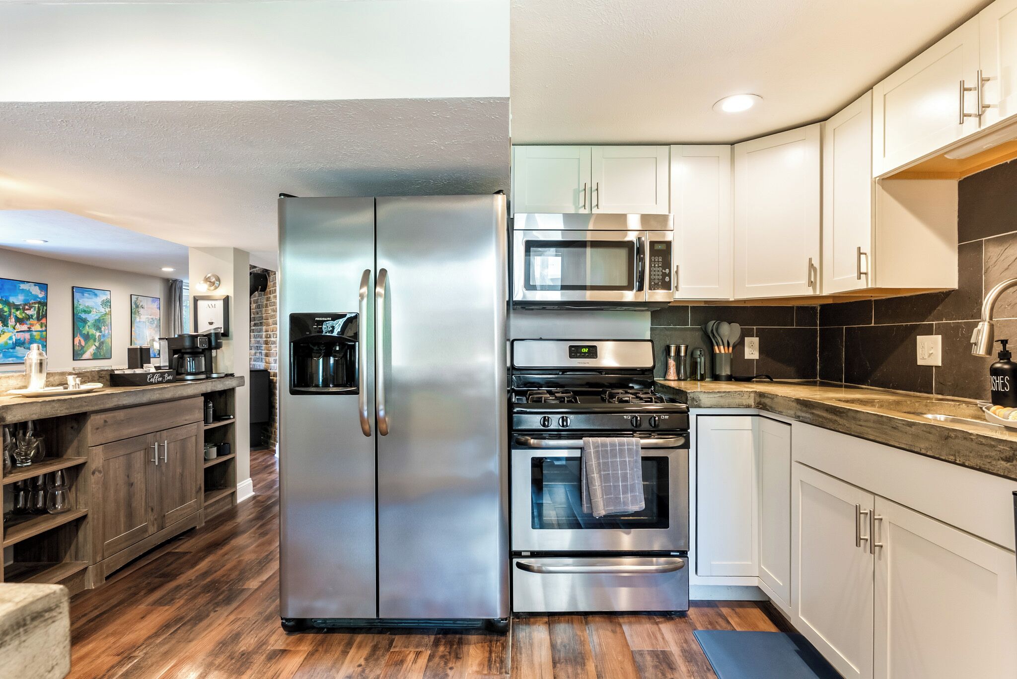 A kitchen with stainless steel appliances, wooden cabinets, and a tiled backsplash.
