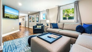 Un salon moderne avec un téléviseur à écran plat, un canapé, une table basse et un tapis bleu à motifs.