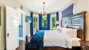 Une chambre à coucher avec un grand lit, un lustre et une vue sur l’extérieur par une fenêtre.