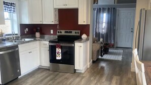 A kitchen with white cabinets, a stainless steel refrigerator, and a wooden floor. - Buckeye Cottage (Willard)