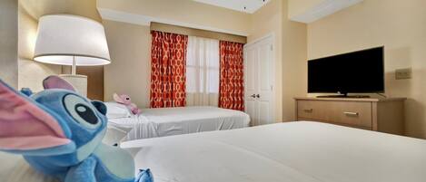 Une chambre d’hôtel avec deux lits, un ventilateur de plafond, une télévision et une lampe.