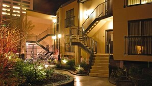 A building with a central staircase, outdoor seating area, and a well-lit entrance.