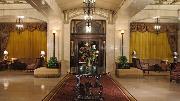 A lobby with a central table, two sofas, and a chandelier.