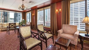 A hotel room with a large window, a chandelier, and a seating area with patterned furniture.