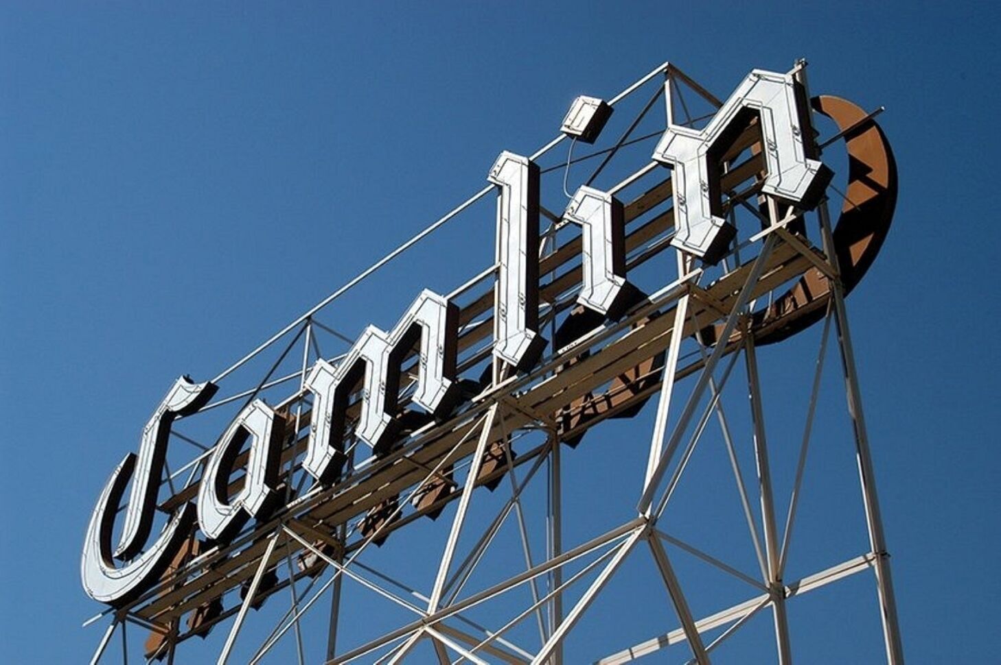Un cartel grande de metal con la palabra "Camlin" sobre un cielo azul despejado.