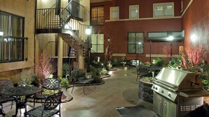 Une cour extérieure dotée d’un escalier central, de plusieurs espaces aménagés pour s’asseoir et d’un barbecue.