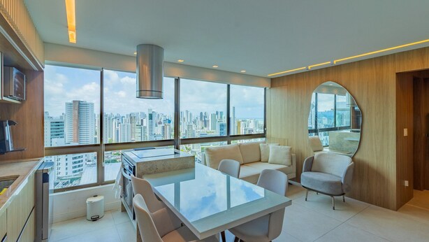 Una sala de estar moderna con una mesa de comedor de vidrio, sofás y un ventanal con vistas a la ciudad.