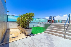 A rooftop terrace with a glass balustrade, a green artificial turf area, and steps leading to a pool. - Homes Stay #2306 - Ideal Location in Carpediem (Recife)