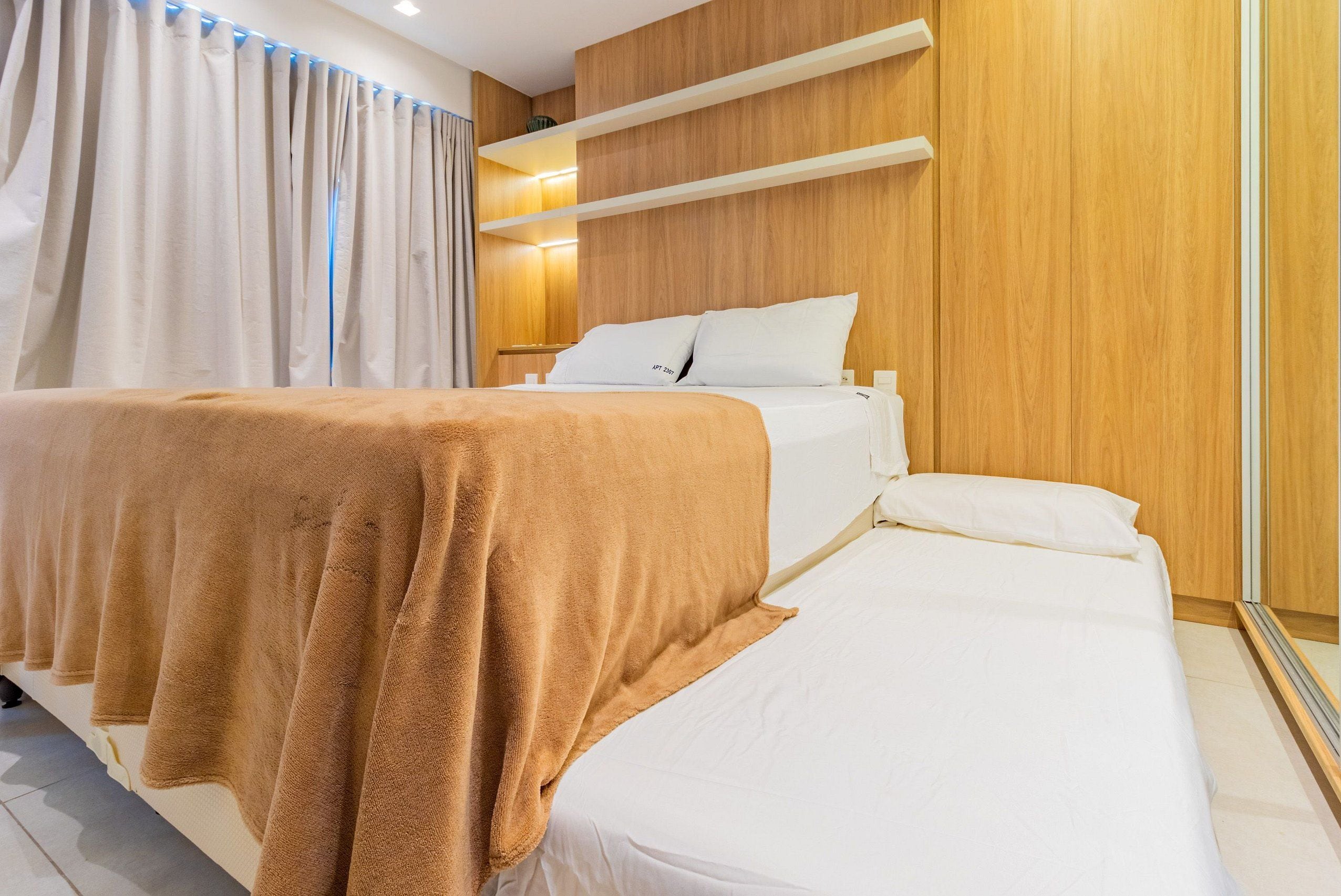 A hotel room with a bed, a wooden headboard, a bedside table, and a mirror.