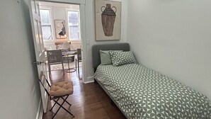 Une chambre à coucher avec un lit, une chaise, un bureau et une fenêtre.
