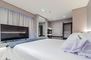 A hotel room with a large bed, a flat-screen TV, a mirror, a bedside table, and a wardrobe. - Homes Stay #2307 - Flat em Recife by Carpediem (Recife)