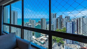 A high-rise hotel room with a large window overlooking a cityscape and the ocean. - Homes Stay #2307 - Flat em Recife by Carpediem (Recife)