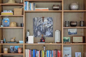 Ein Bücherregal mit Büchern, Dekoration und einem zentralen abstrakten Gemälde.
