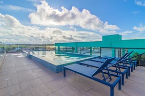 A rooftop pool with blue chairs and a clear sky. - Varandas #415 - Porto de Galinhas por Carpediem (Ipojuca)