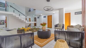 A modern interior with a staircase, a round coffee table, wicker chairs, and a small indoor garden. - Varandas #415 - Porto de Galinhas por Carpediem (Ipojuca)