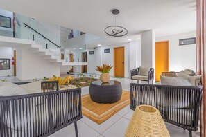 A modern interior with a staircase, a round coffee table, wicker chairs, and a small indoor garden. - Varandas #415 - Porto de Galinhas por Carpediem (Ipojuca)