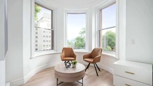 Une pièce moderne avec une table ronde en bois, deux fauteuils en cuir et une commode blanche.