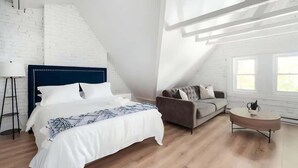 Een slaapkamer met een bed, een bank, een salontafel en een trap.