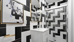 Een moderne badkamer met een zwart-wit tegelpatroon, een witte wastafel en een grote spiegel.