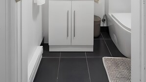 A modern bathroom with a white vanity, a mirror, a toilet, and a shower area.