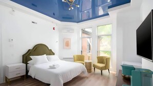 A modern hotel room with a large bed, a television, a desk, and a chair.