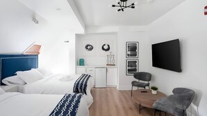 A modern hotel room with a bed, a desk, a chair, and a TV. - The Suites | Downtown Montreal | 2 Beds (Montreal)