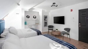 A modern hotel room with two beds, a TV, a desk, and a chair. - The Suites | Downtown Montreal | 2 Beds (Montreal)