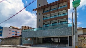 Ein modernes Gebäude mit Glasbalkon, überdachter Eingangsparte und einer sichtbaren Treppe zum Eingang.