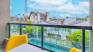 Ein Balkon mit Blick auf einen Swimmingpool, ein Gebäude mit Balkon und ein klarer Himmel.