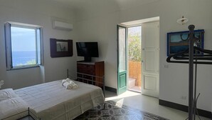 Un dormitorio con cama, televisor, armario, ventana con vistas y suelo estampado.